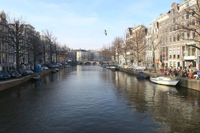 Boats moored in canal amidst buildings in city