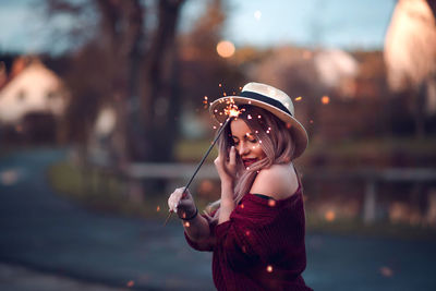 Close-up of woman holding sparkler while standing outdoors