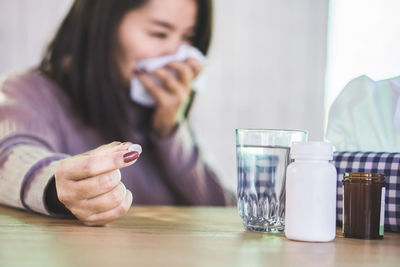 Midsection of woman using mobile phone while sitting on table