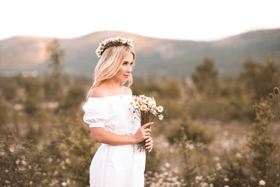 Bride holding flower bouquet standing on field