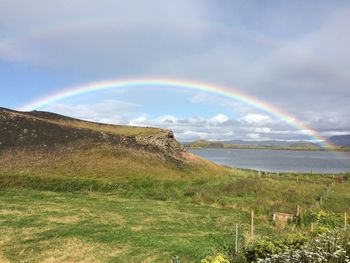 Scenic view of rainbow over sea against sky