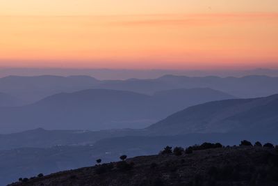 Scenic view of silhouette mountains against orange sky