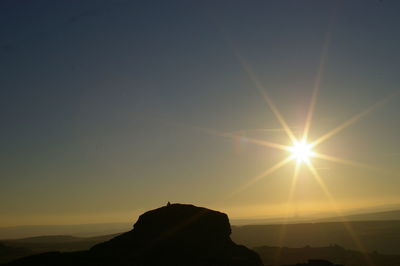 Silhouette rock formation against sky during sunset at dartmoor