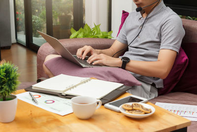 Young man using laptop while sitting on sofa