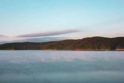 Scenic view of lake by mountains against sky