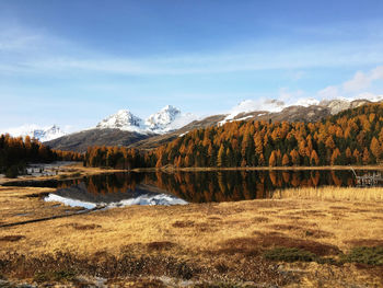 Scenic view of lake by snowcapped mountains against sky