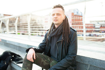 Portrait of hipster sitting at terrace in city