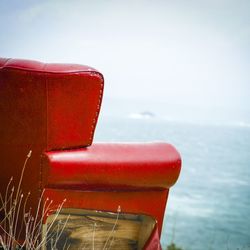 Close-up of red chair against sea