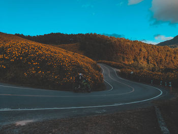 Road amidst trees and mountains against sky