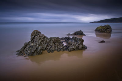 Rock formation in sea against sky