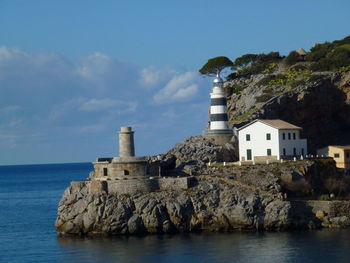 Buildings and lighthose by sea against sky