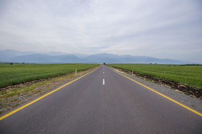 Road amidst field against sky