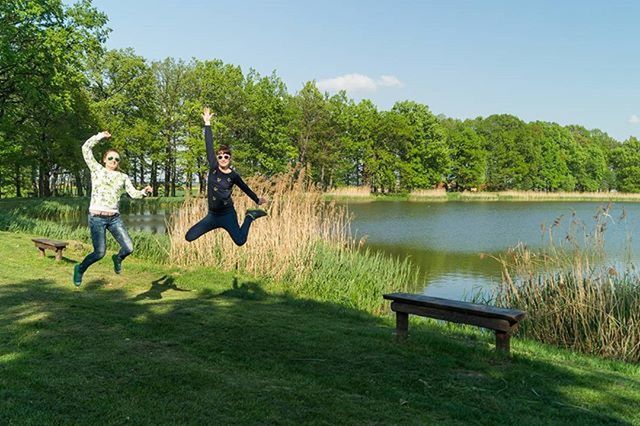 tree, water, leisure activity, lake, lifestyles, tranquility, tranquil scene, grass, scenics, relaxation, nature, full length, bench, beauty in nature, casual clothing, sitting, men, green color