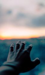 Cropped hand of person against sky during sunset