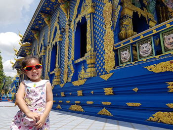 Portrait of smiling woman standing against built structure