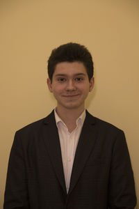 Portrait of smiling businessman standing against yellow background