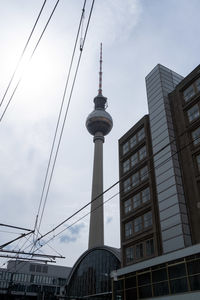 Low angle view of communications tower and buildings against sky