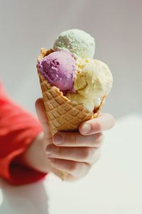 Cropped hand having ice cream cone at table