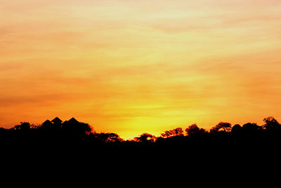 Silhouette trees against dramatic sky during sunset