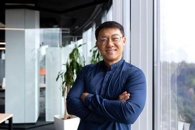 Portrait of young man standing by window