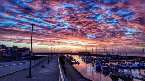 Boats moored at harbor against sky during sunset