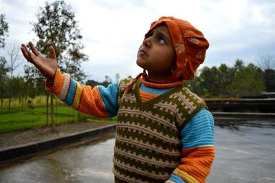 Boy gesturing while standing by pond