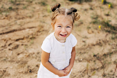 Portrait of a little girl in a white dress in a sand quarry
