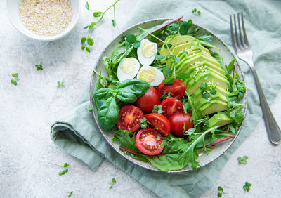 Fresh summer salad with arugula, red cherry tomatoes, basil, eggs and avocado. vegan food. 