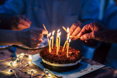 Midsection of people holding burning candles