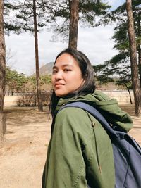 Close-up of young woman against trees