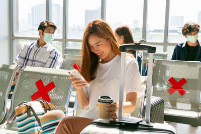 Young woman using mobile phone while sitting on table