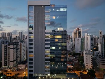 Modern buildings in city against sky at dusk