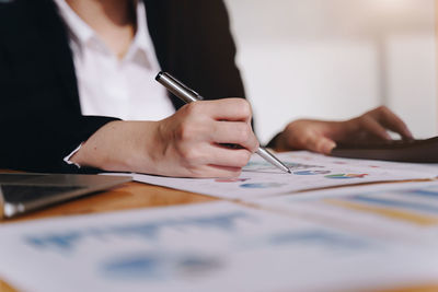 Midsection of woman holding umbrella on table