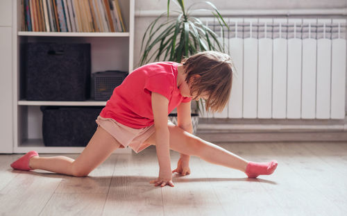 Child learns to sit on the twine at home. girl exercising in the room. 