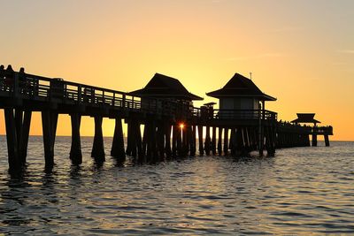 Silhouette pier on sea against clear sky during sunset