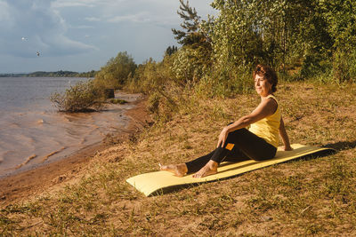 Side view of young woman sitting on land