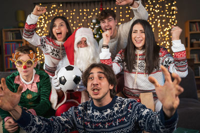 Group of fans watching a sporting event sitting on the sofa in their living room