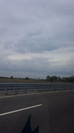 Surface level of empty road against cloudy sky