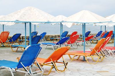 Empty lounge chairs with parasols by sea