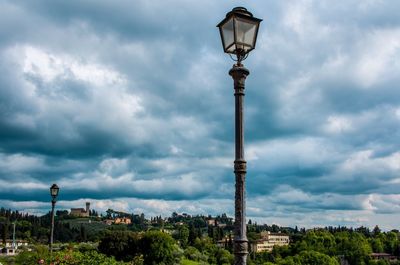 Street light and buildings against cloudy sky