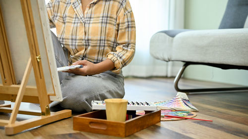 Midsection of man sitting on sofa at home