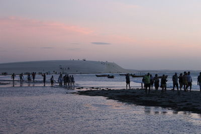 People on beach against sky at dusk