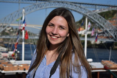 Portrait of young woman smiling while sitting on bridge