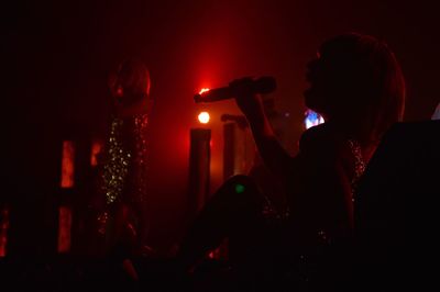 Women singing at nightclub in dark