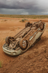 Old abandoned car on field against sky