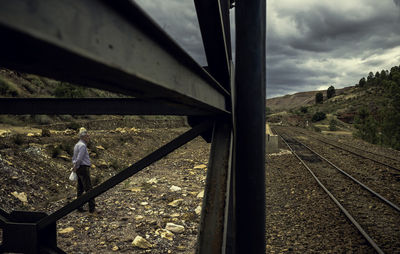 Man walking on railroad track against sky