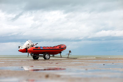 Red boat on beach against sky