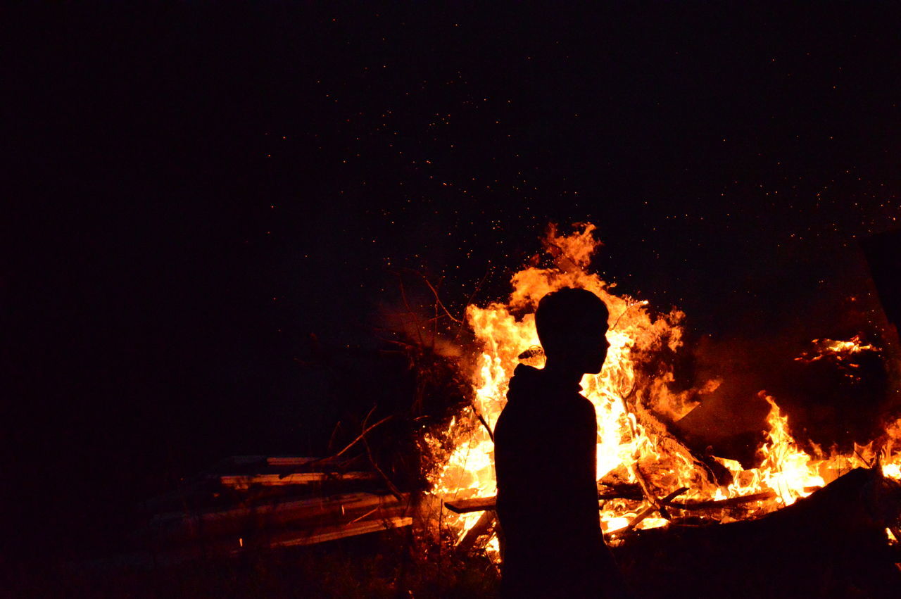 flame, burning, night, real people, heat - temperature, danger, silhouette, one person, men, glowing, motion, standing, outdoors, bonfire, leisure activity, risk, lifestyles, nature, women, sky, people