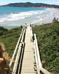 Cropped image of woman standing on footbridge leading toward beach