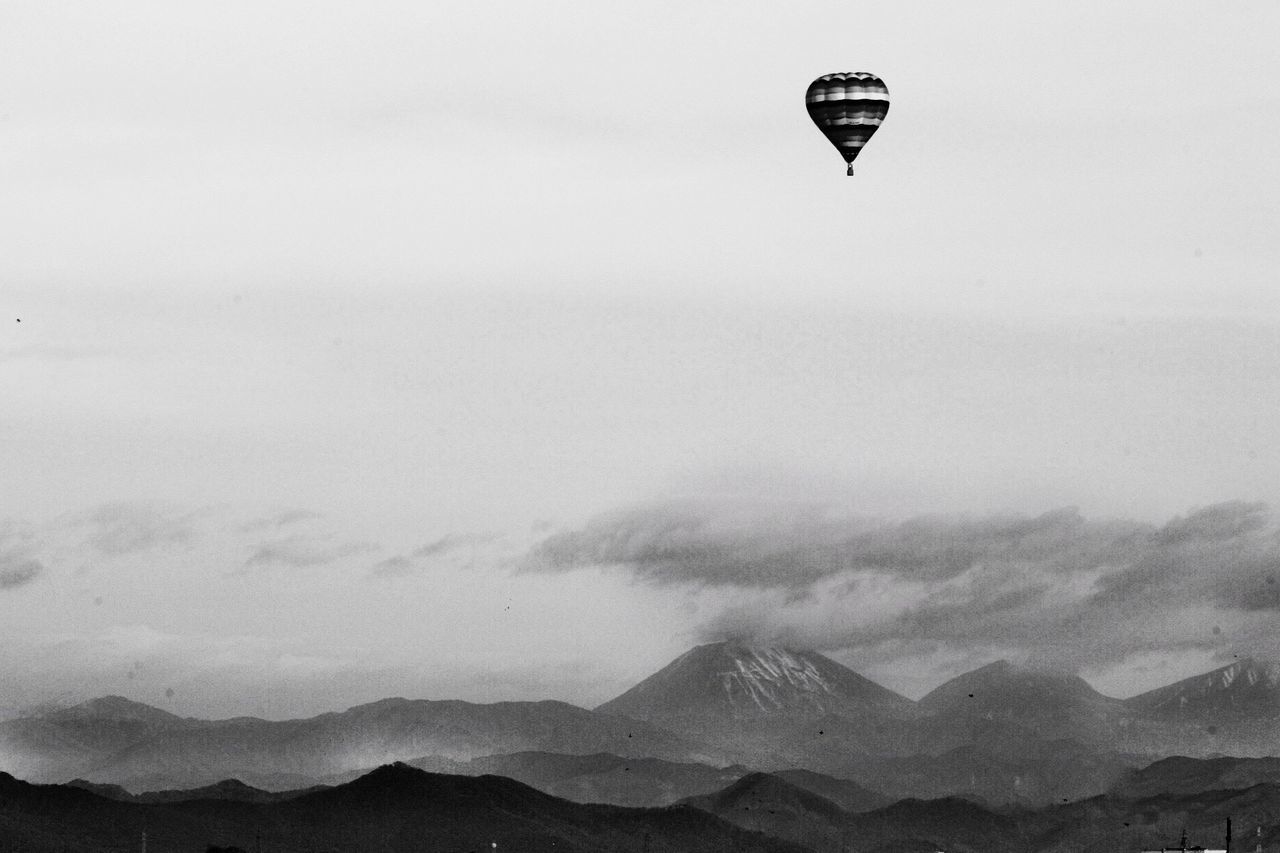 adventure, mid-air, flying, mountain, hot air balloon, clear sky, sky, outdoors, transportation, day, parachute, nature, scenics, landscape, air vehicle, beauty in nature, extreme sports, no people, ballooning festival, paragliding